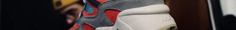 Vibrant red and gray sneakers held in hand, showcasing modern style.