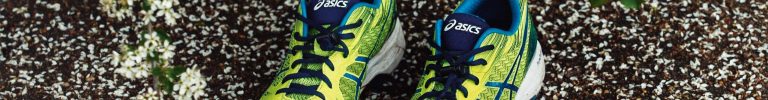 Vibrant green Asics running shoes creatively showcased on a floral background.
